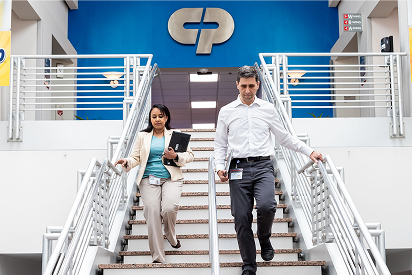 Mitarbeitende von Colgate-Palmolive, die eine Treppe hinuntergehen, mit einem Colgate-Palmolive-Logo hinter ihnen auf einer blauen Wand.